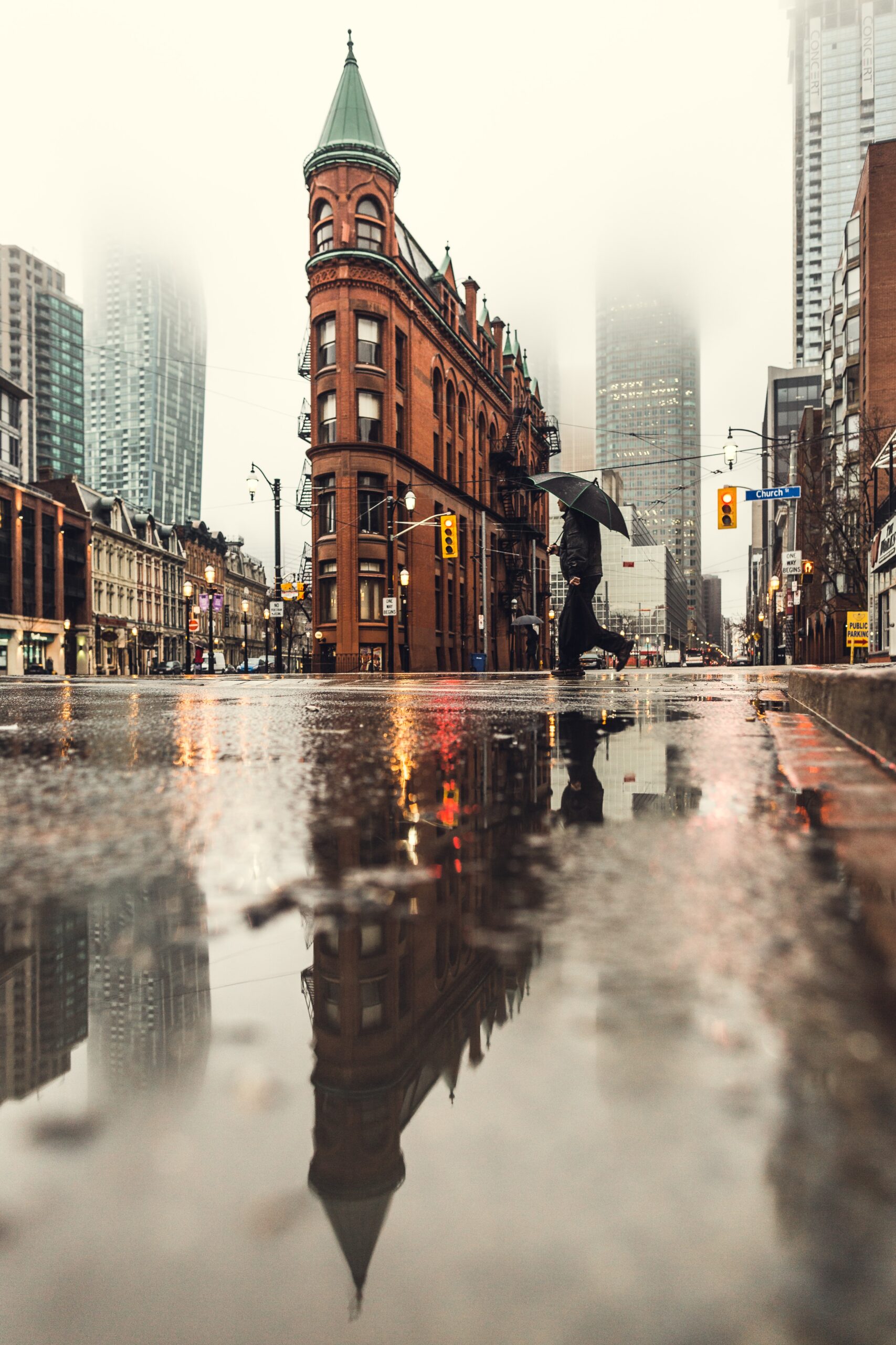 Man using the umbrella, crossing the street during daytime