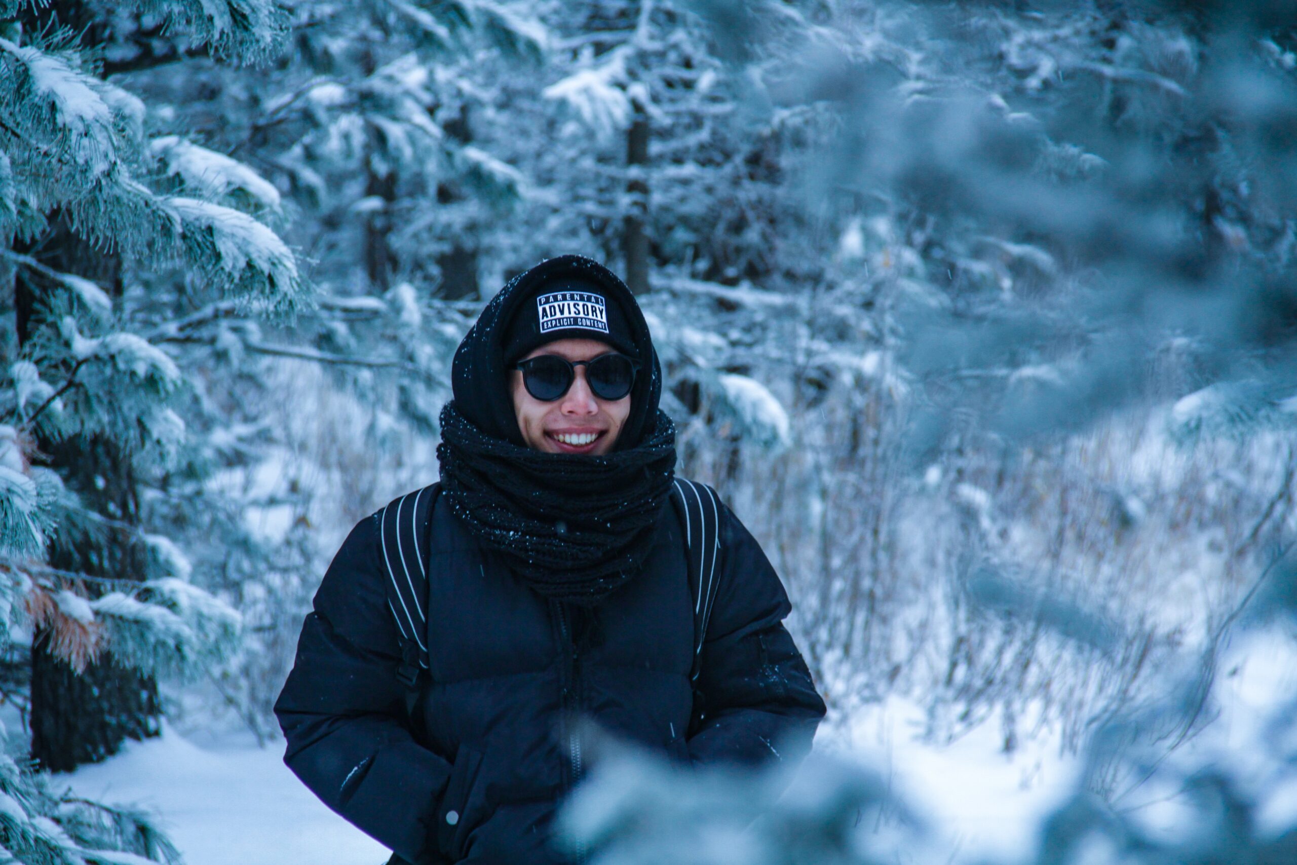 A smiling man standing near snow-tree-covered trees