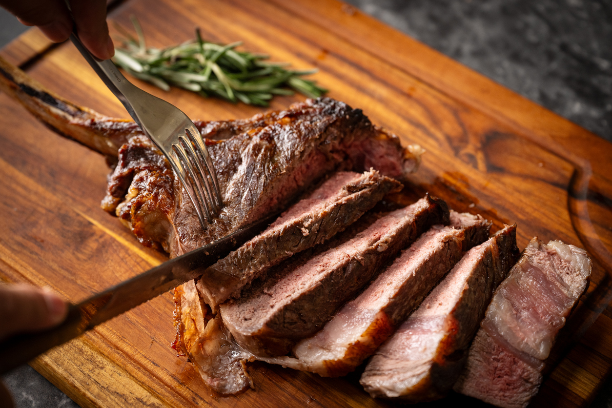 slicing tomahawk steak with knife