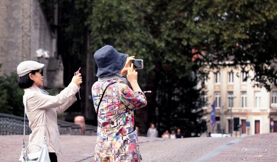 two women taking photos using smartphone, modern street photography