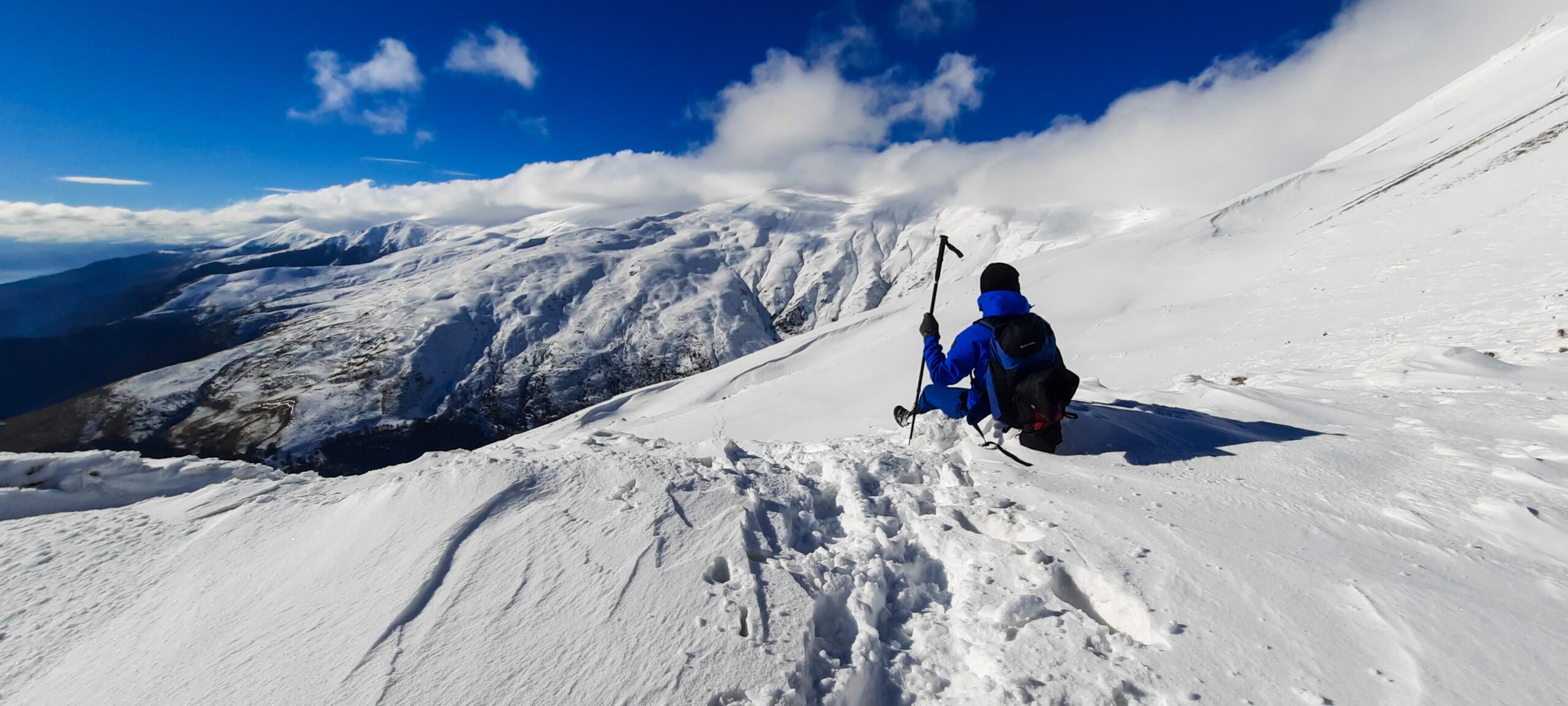 A person in a blue jacket and black pants on a snow-covered-mountain