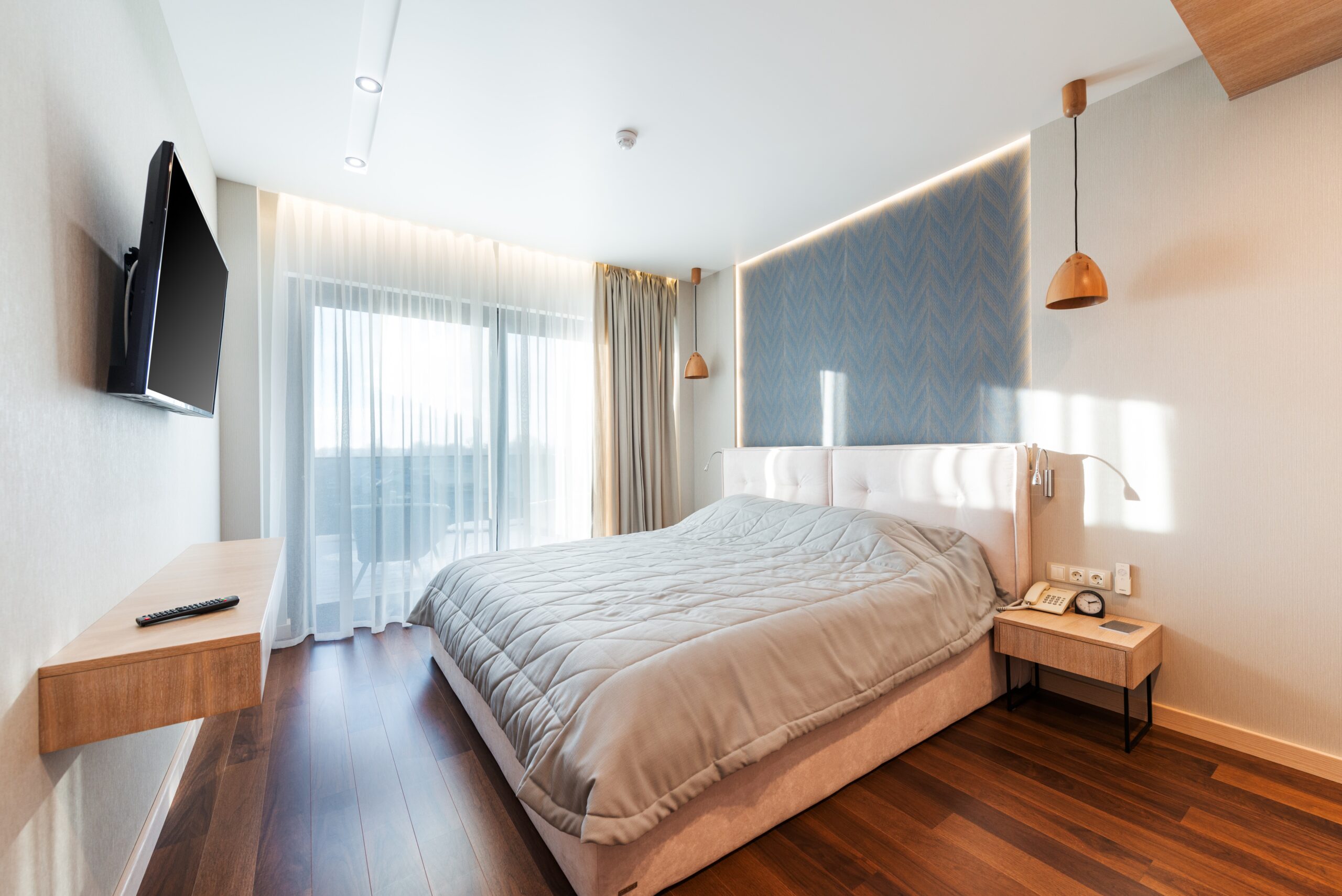 bedroom interior with bed and nightstand and parquet floor in sunlight 
